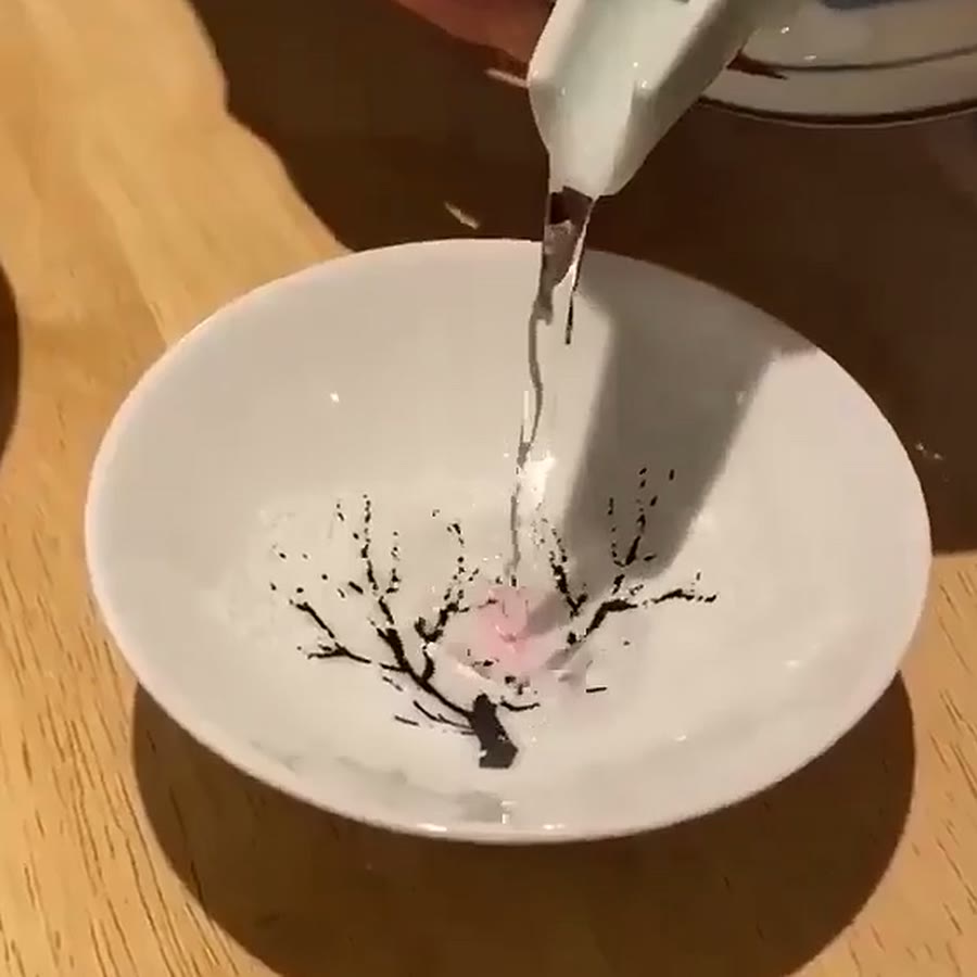 The cup before the pour: white ceramic with a bare ink tree